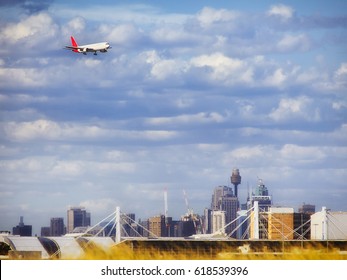 Large Commercial Passenger Airplane Approaching Sydney International Airport For Landing In View Of City Towers And Landmarks.