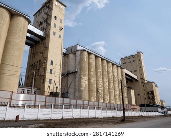 Large concrete grain elevator building against a clear blue sky, industrial agricultural storage facility for grain processing and farming.
