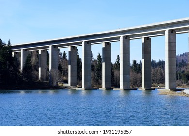 A large concrete overpass bridge built over a beautiful natural forest landscape along the lake