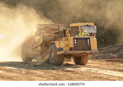 Large construction scraper moving soil for a new commercial housing development