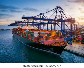 A large container cargo ship is beeing loaded in a commercial dock during sunset