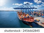 A large container cargo vessel is beeing loaded and unloaded by large cranes in a commercial dock