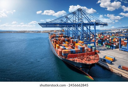 A large container cargo vessel is beeing loaded and unloaded by large cranes in a commercial dock - Powered by Shutterstock