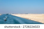 Large container ship, accompanied by tugboat, passing through the Suez Canal in Egypt.