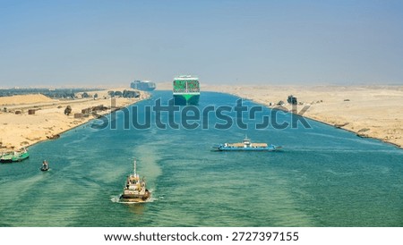 Large container ship, accompanied by tugboat, passing through the Suez Canal in Egypt.