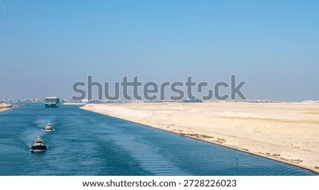 Large container ship, accompanied by tugboat, passing through the Suez Canal in Egypt.