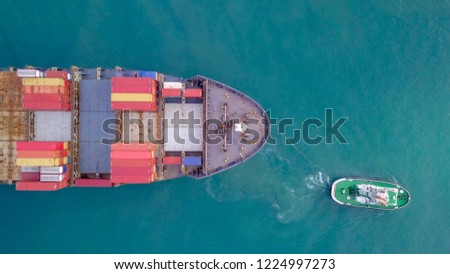 Large container ship pulled into port by a tugboat - Top down aerial image