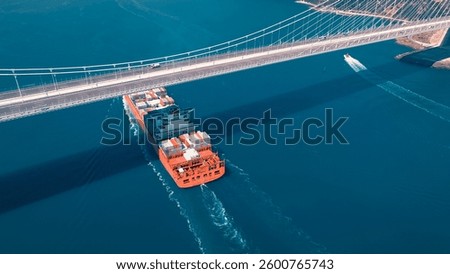 Large container ship sails under the YSS Cable Bridge. 300 meters long cargo vessel heading towards the Istanbul. Aerial Bosphorus Sea.