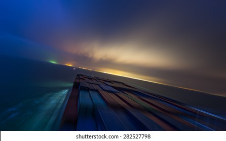 Large Container Vessel Ship Approaching Coast Line By Night. Motion Blur