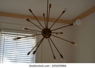 Large Copper Pipe Sputnik Style Pendant Light Chandelier In White Walled Room Next To Window With White Blinds.