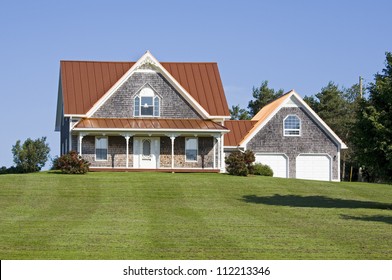 A Large Country House With A Bronze Steel Roof And An Expansive Lawn.