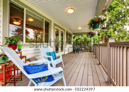Large covered porch with railings ,outdoor seats, flower pots and turned on lights on the ceiling. Northwest, USA