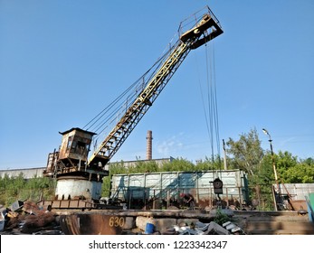 A large crane hauls scrap metal using its electromagnet.