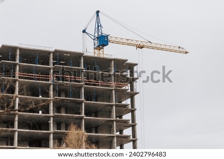 A large crane, painted in the Ukrainian colors of yellow and blue, is building a new building in Ukraine against the sky. Restoration after the war. Photography, construction concept, industry.