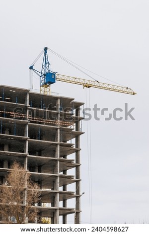 A large crane, painted in the Ukrainian colors of yellow and blue, is building a new building in Ukraine against the sky. Restoration after the war. Photography, construction concept.
