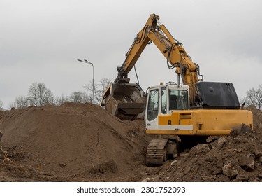 A large crawler excavator sifting soil at a construction site. An excavator with a special, hydraulic, rotating "sieve" at the end of the arm, sorts the ground into fractions on a large construction .