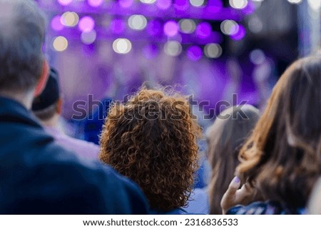 Large crowd of people watching concert,festival summer time,blurred background.Rear view.