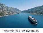 Large cruise ship sails across the sea towards the mountains. Back view. Drone