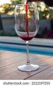 Large Crystal Glass Into Which Red Wine Is Poured. High Class Pool Party Concept. Alcoholic Beverage.