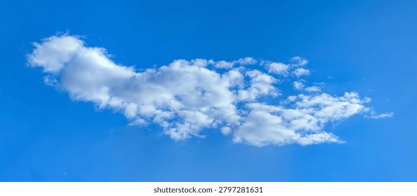 A large cumulus cloud. Clouds flowing lazily like cottony fibers against a clear, serene blue background. The sky speaks of calm, peace, and silence.