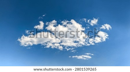 A large cumulus cloud. Clouds flowing lazily like cottony fibers against a clear, serene blue background. The sky speaks of calm, peace, and silence.