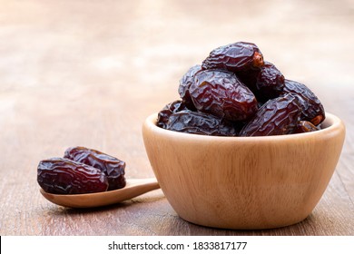 The large date fruits (Medjool) in cups and wooden spoons on a cement with blurred background. - Shutterstock ID 1833817177