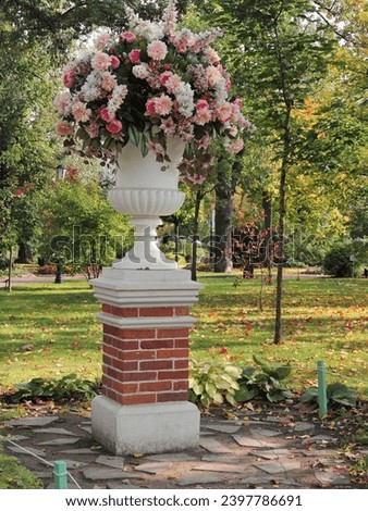 Large decorative vase with fresh flowers in a city park in the autumn season