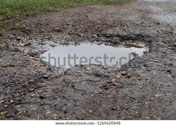 Large deep pot hole in the road. Wisbech Norfolk\
UK. wet poor maintenance. Dangerous to traffic. Damage to\
vehicles