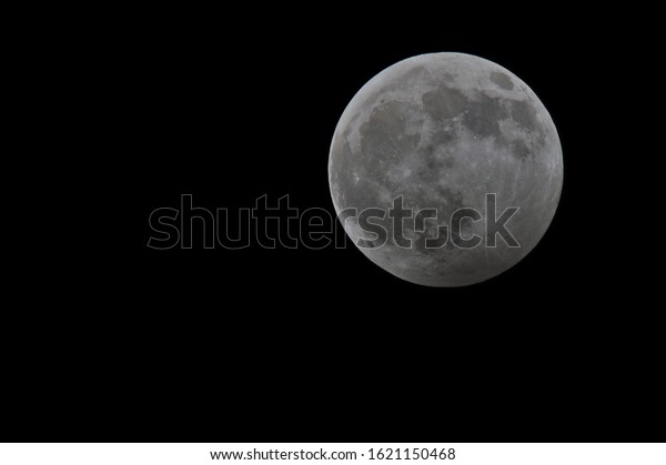 Large detailed full moon in the night sky on\
black background.