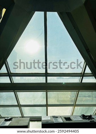 A large diamond-shaped window inside the museum on a sunny day