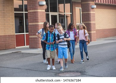 Large, diverse group of kids leaving school at the end of the day. School friends walking together and talking together on their way home