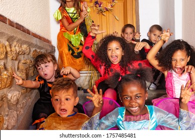 Large Diverse Group Of Spooky Looking Kids In Halloween Costumes Standing In Front Of The Door Of The House