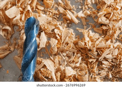 Large drill bit surrounded by wood chips