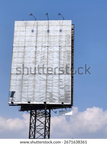 Large empty billboard structure with weathered surface and metal frame against a blue sky