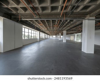 A large, empty office building interior with plenty of windows and exposed industrial pipes on the ceiling. - Powered by Shutterstock