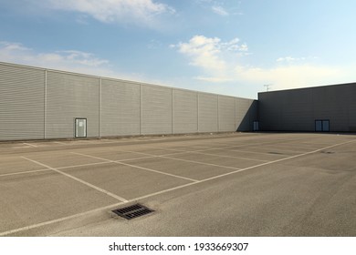 Large Empty Parking Lot Bordered By Long Aluminum Clad Walls. Background And Texture. Copy Space