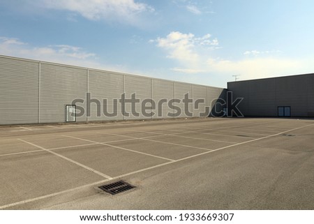 Large empty parking lot bordered by long aluminum clad walls. Background and texture. Copy space