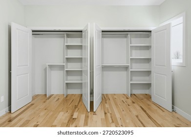 Large, empty room with two closets, one on the left and one on the right. The closets are open, revealing shelves and cabinets filled with clothes and other items. The room has a clean