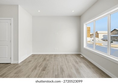 Large, empty room with a window and a door. The room is very clean and has a very simple design