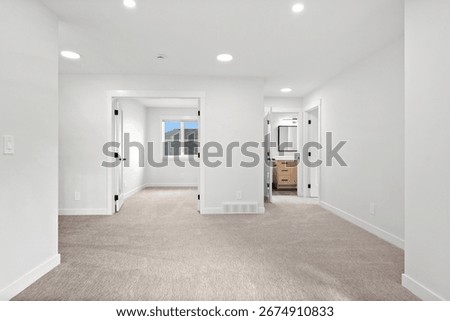 Large, empty room with a window and a door. The room is white and has a carpeted floor