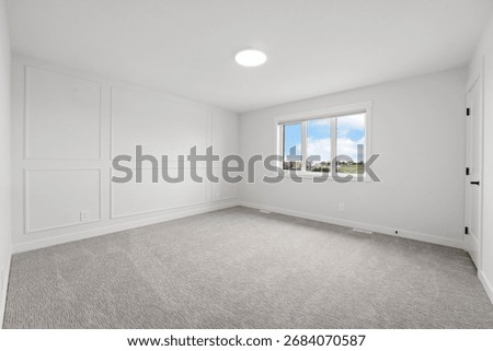 Large, empty room with a window and a light fixture. The room is white and has a clean, minimalist look