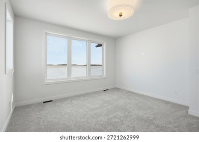 Large, empty room with a window overlooking a lake. The room is white and has a clean, minimalist feel
