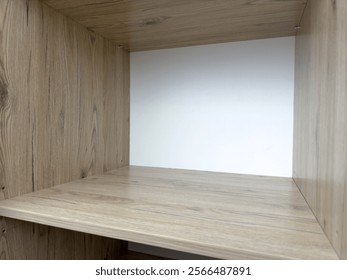 Large empty square shelf inside closet with open door, free space for storing clothes in wooden shelf of closet in house. Filling space with clothes after moving into new home
