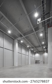 Large empty warehouse with a regular structural grid, polished floor and deep industrial volume.