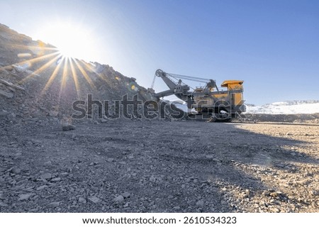 Large excavator work in open pit coal mine during at sunrise.