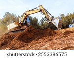 Large excavator works diligently, moving earth, debris at during construction site surrounded creating dusty atmosphere.