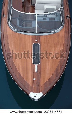 Large expensive varnished wooden boat top view. Front deck Luxurious lacquered wooden big boat on the water top view.