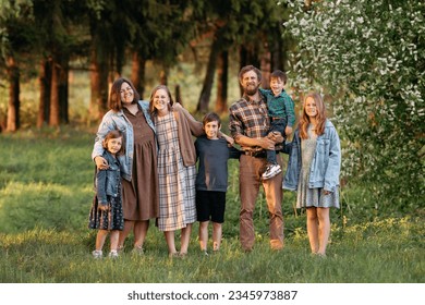 Large family of father, mother, two brothers and three sisters standing and sitting on a green field in summer, full length portrait. - Shutterstock ID 2345973887