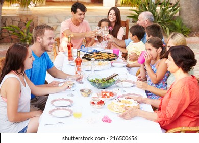 Large Family Group Enjoying Meal On Terrace Together