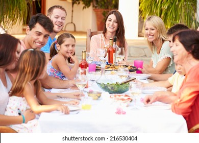 Large Family Group Enjoying Meal On Terrace Together